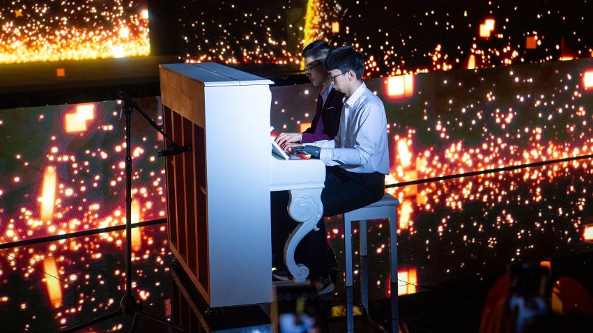 智能仿生手使用者古月與少年鋼琴家舒海峰合奏。主辦方供圖